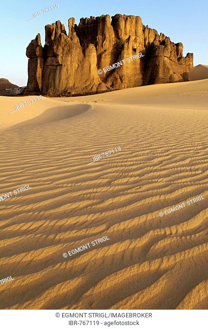 Eroded rock formations rising out of desert sand dunes, ripples in Tin Akachaker, Tassili du Hoggar, Wilaya Tamanrasset, Sahara Desert, Algeria, North Africa