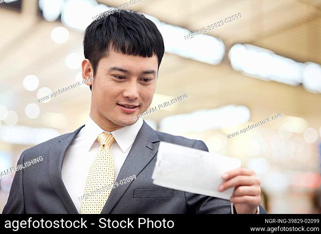 Young business man looking at flight ticket