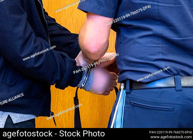 19 January 2022, Bavaria, Landshut: The defendant's handcuffs are removed in the hearing room of the district court. The prosecution accuses the 25-year-old man...