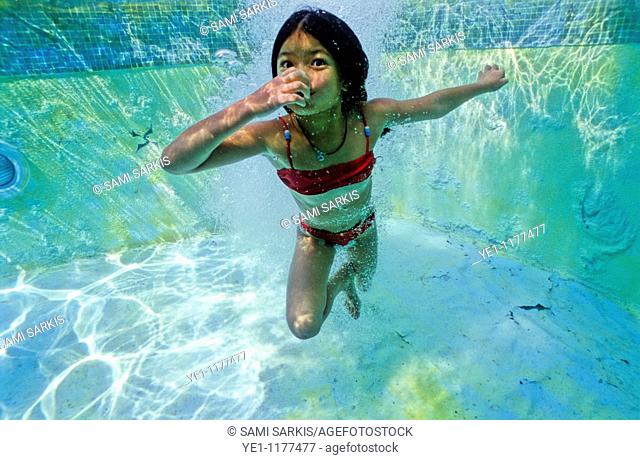 Young girl holding her breath underwater in a swimming pool, Provence, France