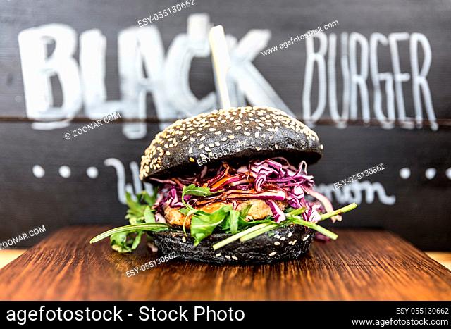 Black healthy vegetarian salmon burger beeing sold on open kitchen, odprta kuhna, international food festival event. Street food ready to be served on a food...