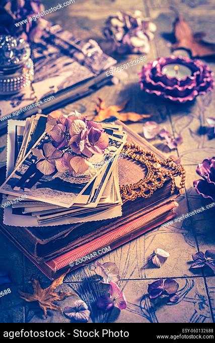 Memories - old family photo album with necklace, old books and dried flowers and candles