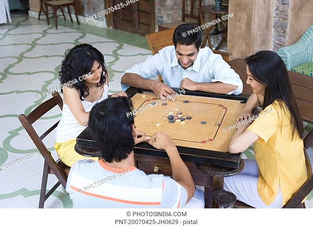 High angle view of two young men and two young women playing carom