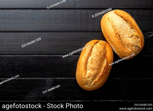 Two mini french baguettes on black table. Top view