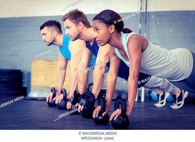 Three muscular athletes on a plank position