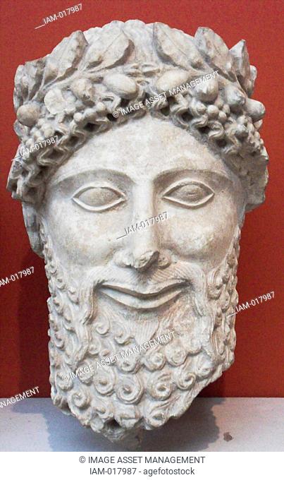 Limestone head of a statue of a bearded worshipper. Made in Cyprus 475-450 BC. From the sanctuary of Apollo at Idalion. He wears a laurel wreath with beads or...