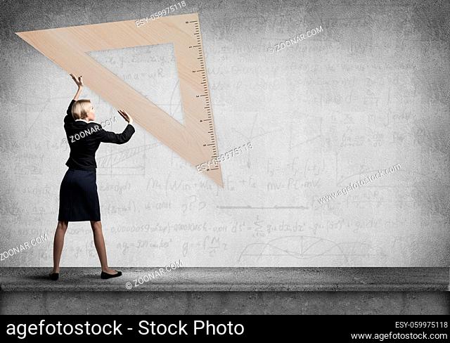 Woman holding big ruler on wall background. Testing and examination concept. Businesswoman measuring something with ruler. Human resources recruitment