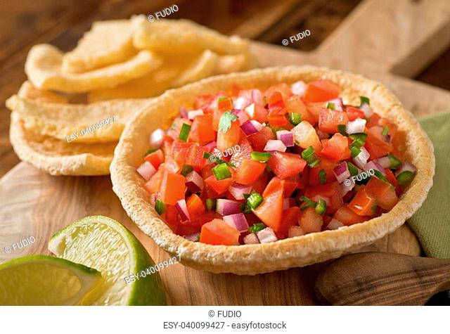 Fresh tomato salsa with serrano pepper, red onion, green onion, lime, and cilantro in a tortilla bowl