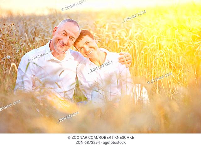 Paar Senioren macht Urlaub in der Natur und sitzt glücklich in einem Weizenfeld