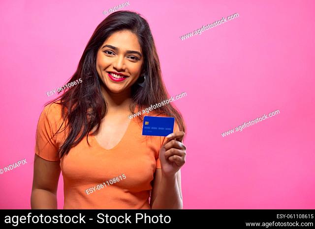Young woman showing credit card in front of camera with smile