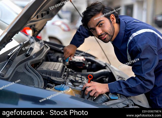 A MECHANIC REPAIRING A CAR AND LOOKING STRAIGHT