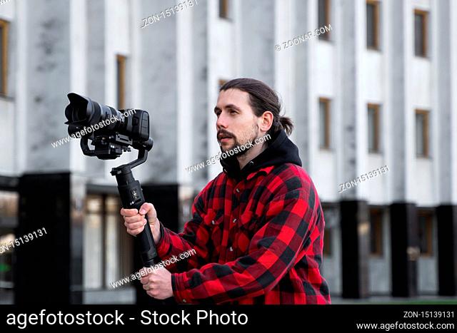Young Professional videographer holding professional camera on 3-axis gimbal stabilizer. Pro equipment helps to make high quality video without shaking