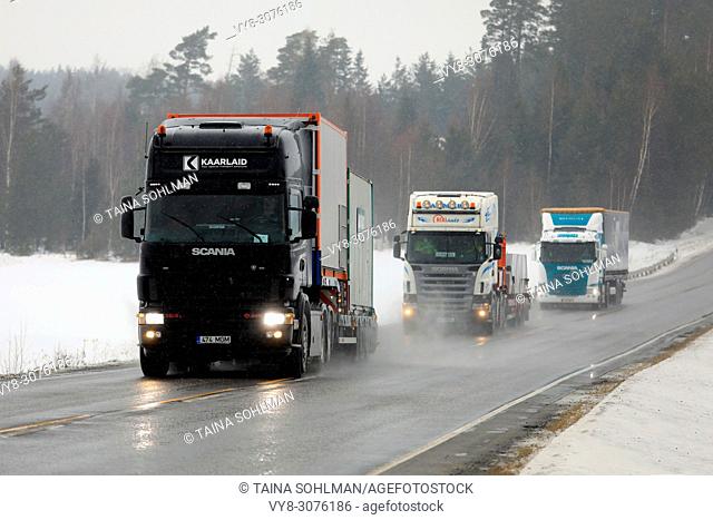 Two special transport semi trucks and a cargo semi trailer move along highway in South of Finland in challenging winter weather conditions