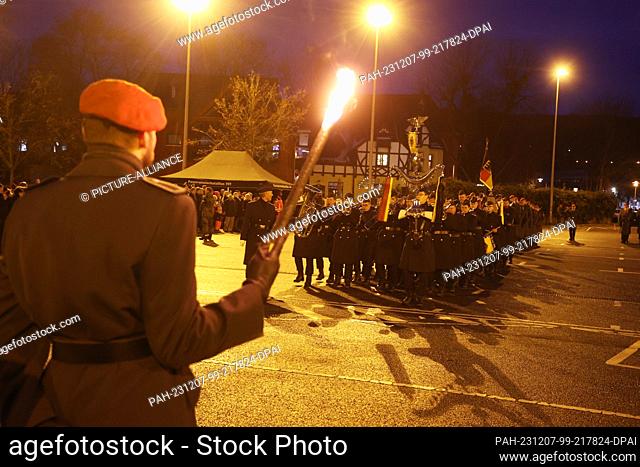 07 December 2023, Thuringia, Gera: A Bundeswehr soldier stands with a torch in his hand at the public swearing-in ceremony for around 100 recruits of the 5th...