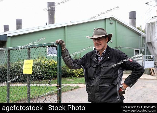 01 October 2020, Mecklenburg-Western Pomerania, Penkun: Bernd Klänhammer, farmer, is standing in front of his pigsty next to the fence with the sign ""Stop...