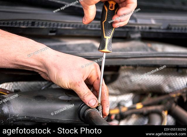 Auto mechanic working on car engine at repair service. Close up view