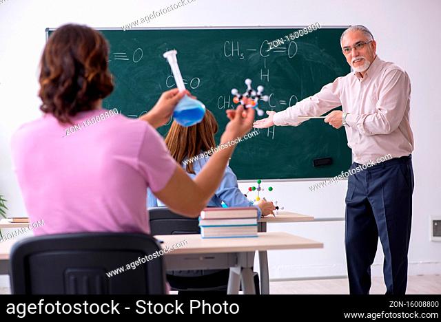 Old teacher and two students in the classroom