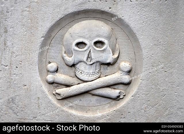 Ein Steinrelief mit Totenschaedel und gekreuzten Knochen erinnert den Betrachter an die Vergaenglichkeit irdischen Lebens. Querformat