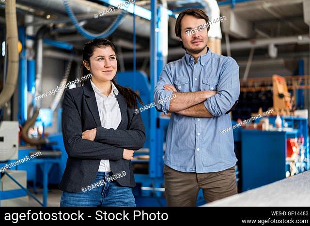 Confident expertise team looking away while standing with arms crossed at industry
