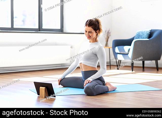 young woman with tablet pc doing yoga at home