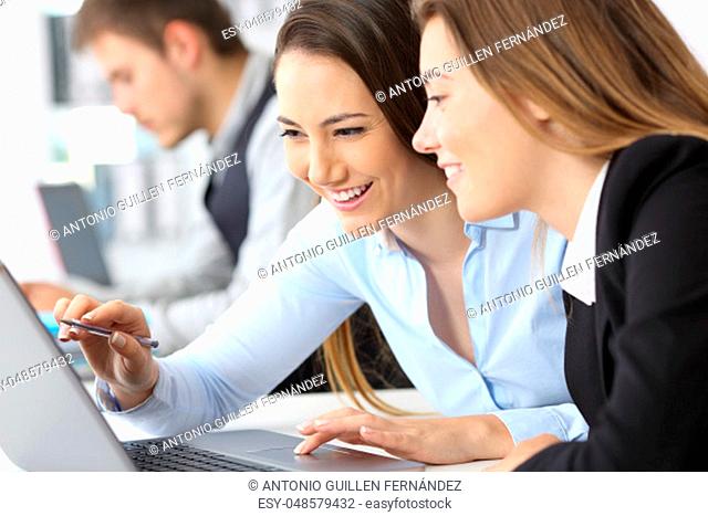 Two businesswomen working together on line with a laptop at office