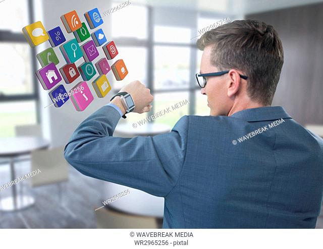 Businessman holding arm with watch and apps icons to eyes in office
