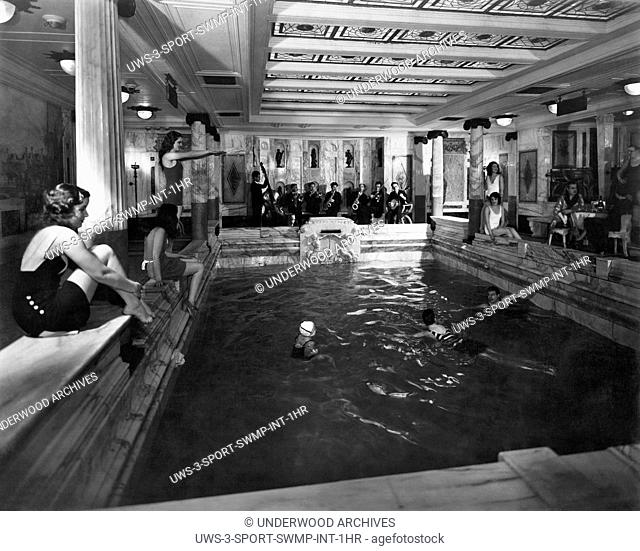 Italy: c. 1927.First class passengers lounging around their indoor pool with a jazz band on the Italian passenger liner MS Vulcania