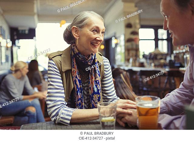 Affectionate couple holding hands and drinking beer at table in bar