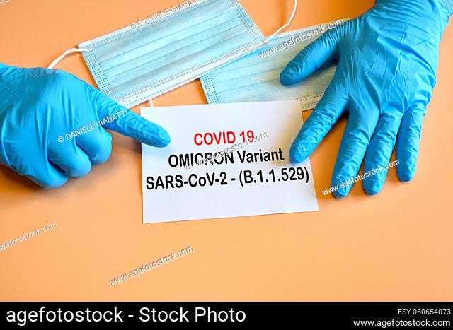 Covid-19 new Omicron variant. Doctor hand with blue glove indicate written ""Covid-19 variant Omicron"" on white paper. Medical face masks for protection for...