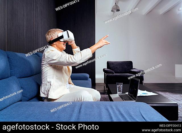 Senior businesswoman gesturing while using virtual reality headset on sofa