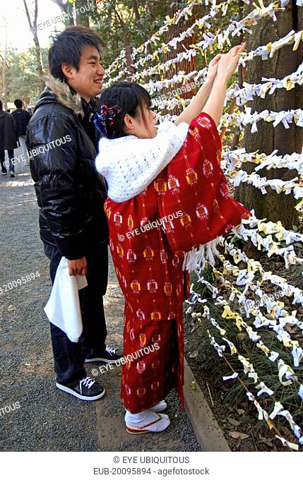 Jingumae - at Meijijingu shrine, couple boy and girl early twenty years old, girl in traditional kimono and wrap, boy in down jacket, jeans, sneakers