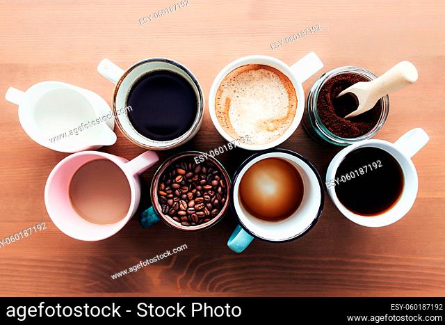 Multiple coffee cups and multicolored mugs with americano, espresso, latte and cappuccino, milk jar, roasted coffee beans in glass bottle