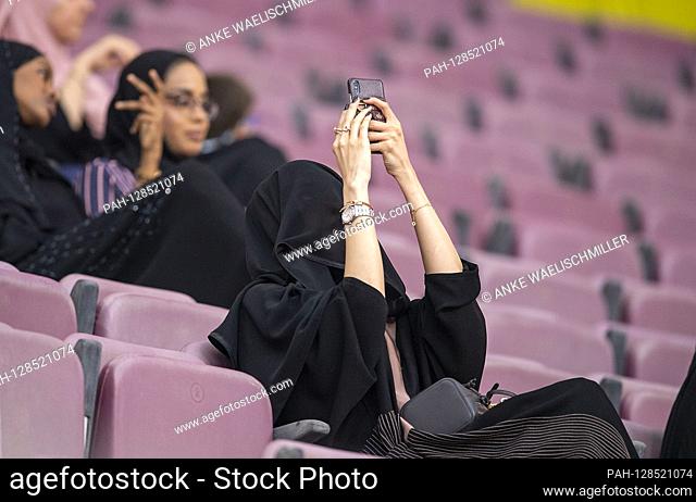 a woman with Schleicher and a cell phone as a spectator, on 03.10.2019 World Athletics Championships 2019 in Doha / Qatar, from 27.09. - 10.10.2019