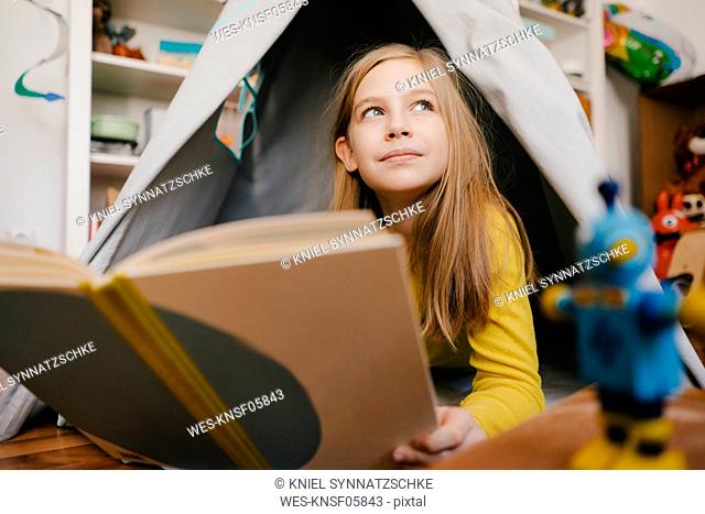 Girl at home reading book in children's room