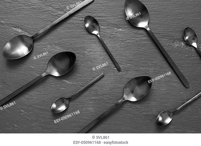 Set of black steel spoons on slate. Top view point, flat lay