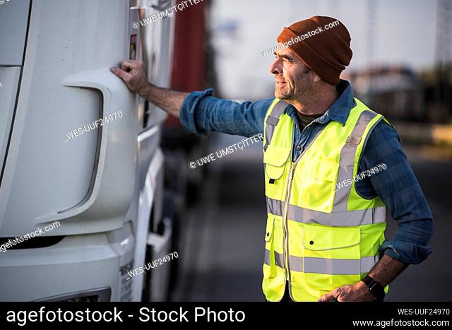Male driver standing by truck at commercial dock