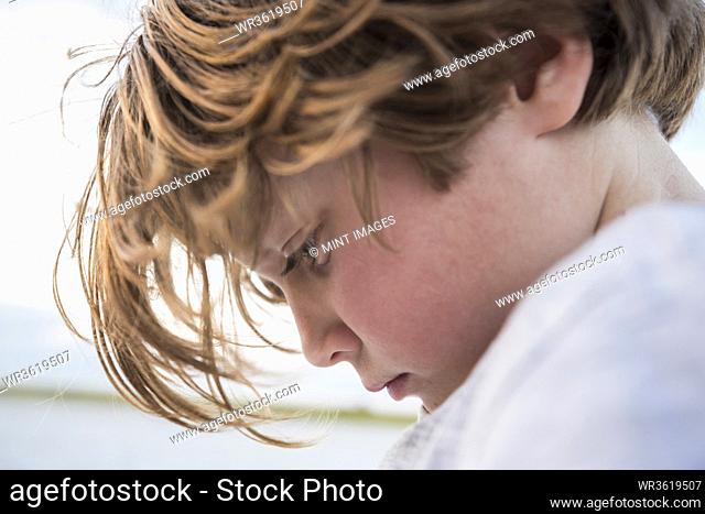Close up profile of a 6 year old boy looking down, head and shoulders