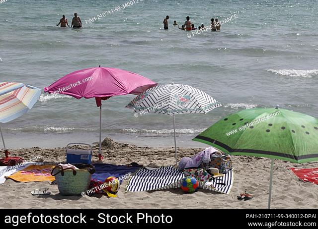 11 July 2021, Spain, -: People bathe in the sea at the beach Playa de Muro in the north of Mallorca. The federal government has declared all of Spain with...
