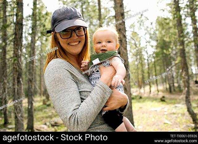 Portrait of smiling woman with baby son (6-11 months) in forest, Wasatch-Cache National Forest