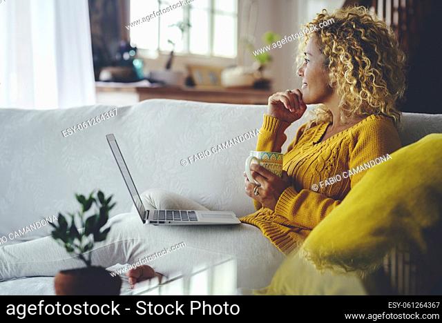 Home leisure activity concept lifestyle. Woman relaxing and using laptop sitting on the sofa. People and online social network life