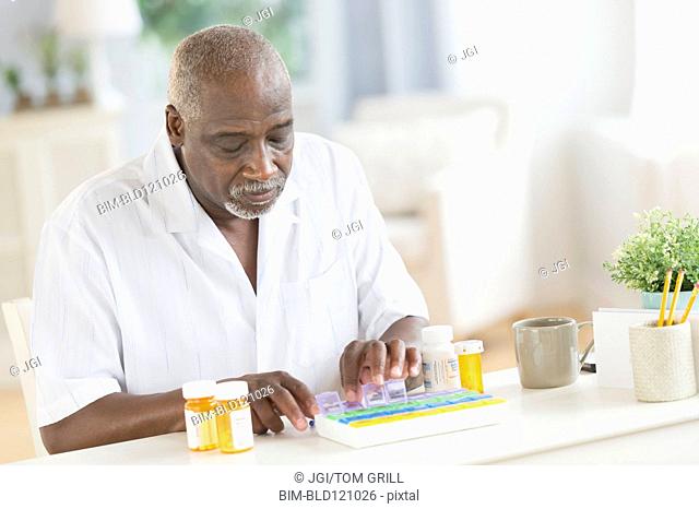 Black man counting pills in pill boxes