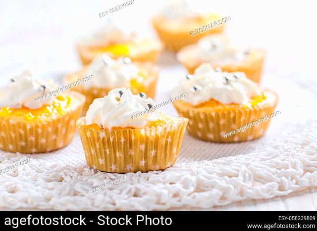 Homemade lemon curd cupcakes with whipped cream on kitchen table