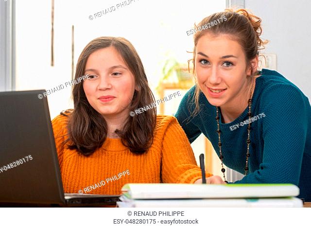 a young woman helps a teen girl with homework