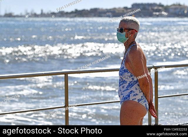 Little going on on Tamariz Beach in Estoril on 08/21/2020. An elderly woman with face mask, mask in a bathing suit looks out to sea