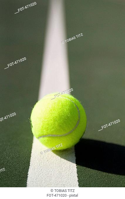 A tennis ball lying on a white line