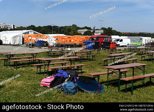 07 September 2021, Bavaria, Munich: Backpacks, beer benches and trailers with the inscription ""Geschirrmobil"" stand in blue sky and sunshine in the area of...