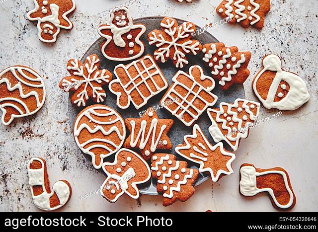 Fresh and tasty Christmas gingerbread cookies placed on white rusty table. Different shapes. Santa claus, snowflake, tree, gift, snowman