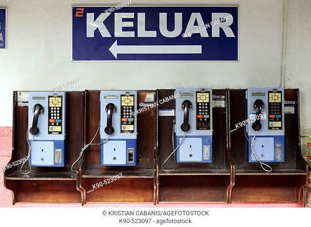 Public phones at train station with 'Keluar' (Exit) sign. Djakarta, Indonesia