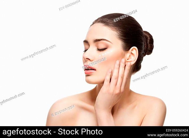 Beautiful young woman with moisturizing cream dots on face. Isolated over white background. Copy space
