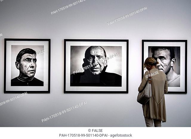 A visitor takes a look at pictures by Stephan Vanfleterenan that show Eddy Merckx (L-R), Briek Schotte and JoJohan Musseeuwat at the photography exhibition Myth...